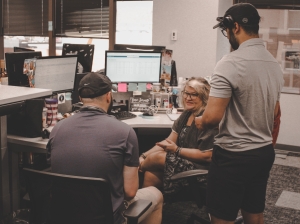 Coworkers gathered around a computer near a work desk