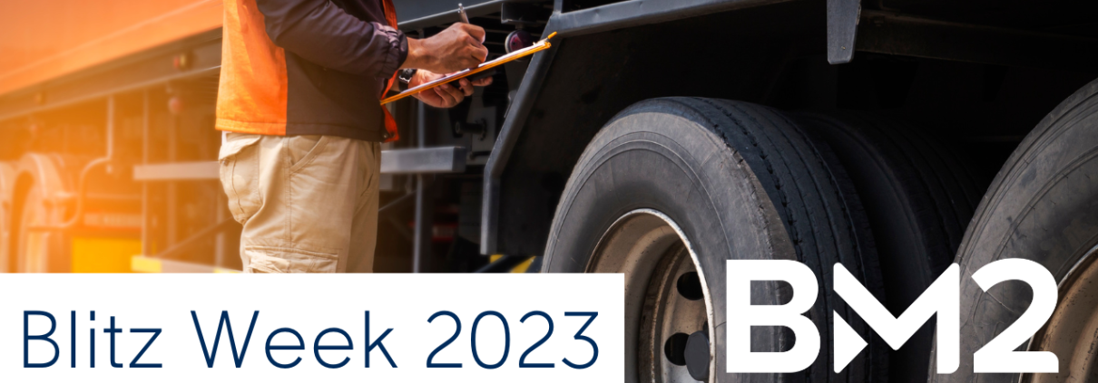 Trucker checking tire on semi while holding a clipboard