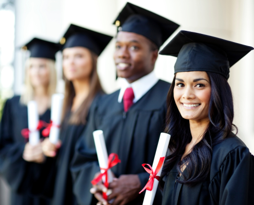 a line of students wearing graduation caps and gowns holding diplomas