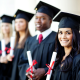 a line of students wearing graduation caps and gowns holding diplomas