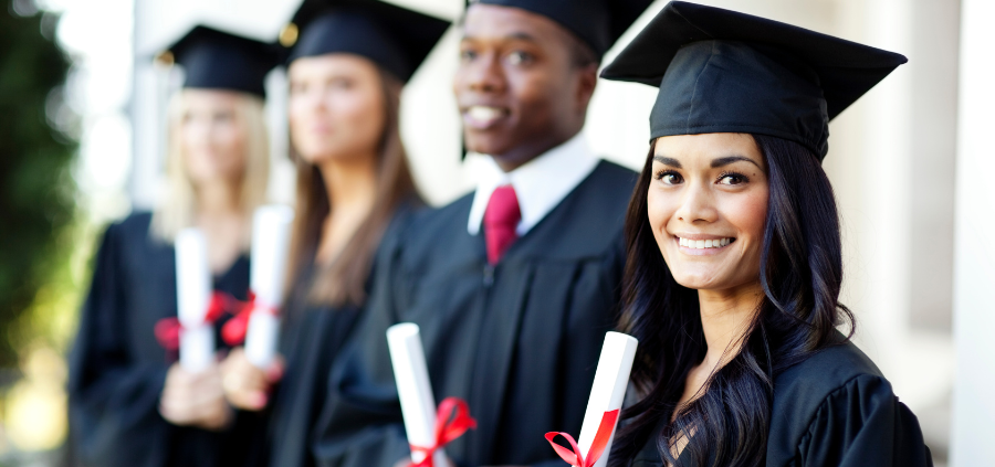 a line of students wearing graduation caps and gowns holding diplomas