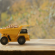 Yellow toy dump truck filled with pebbles on a wooden table