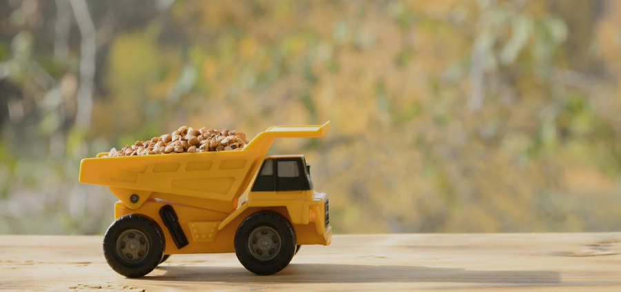 Yellow toy dump truck filled with pebbles on a wooden table