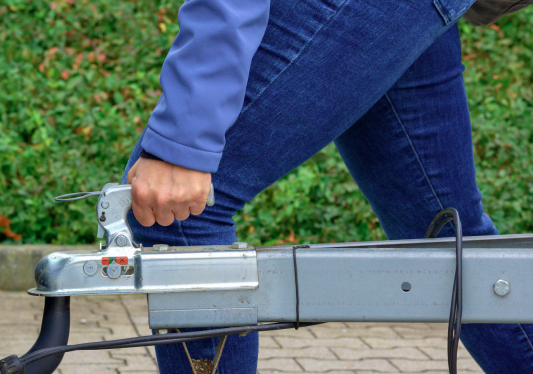Person's hand lifting up a drop trailer handle for a truck hitch